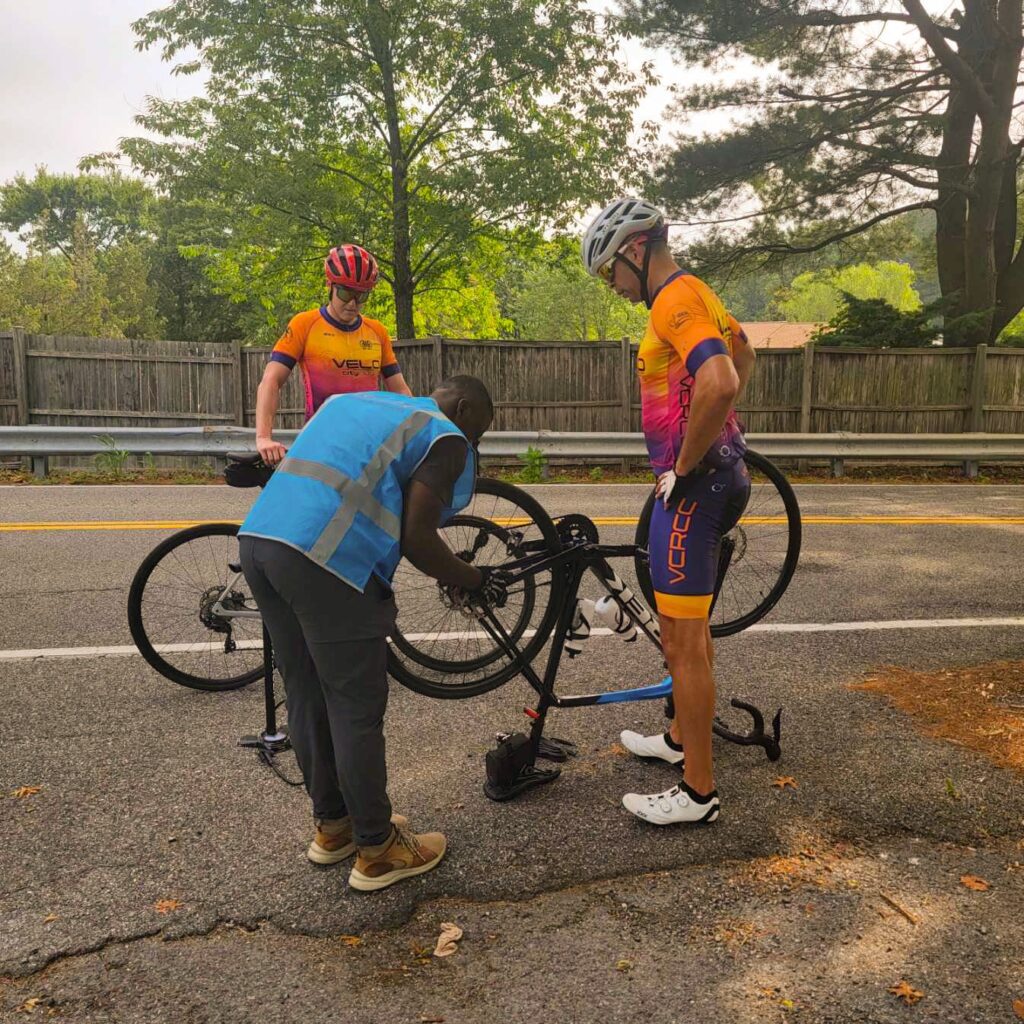 A man is fixing his bike on the side of the road